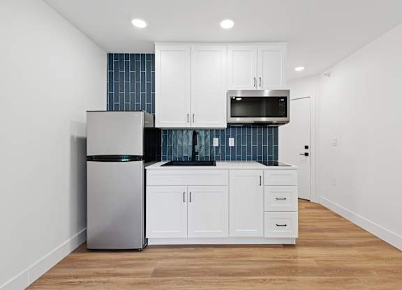 A kitchen with white cabinets and a stainless steel refrigerator.
