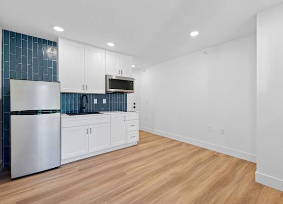 A kitchen with white cabinets and a stainless steel refrigerator.