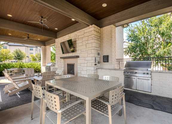 A patio with a table and chairs and a grill.