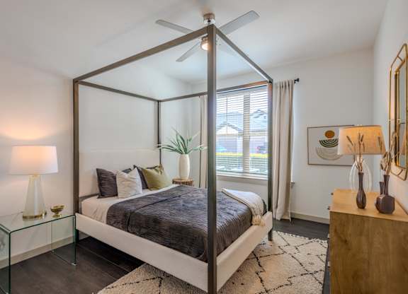 A bedroom with a bed in the center and a ceiling fan above it.