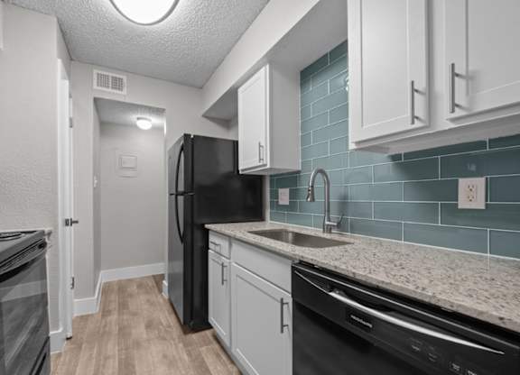 A kitchen with black appliances and white cabinets.