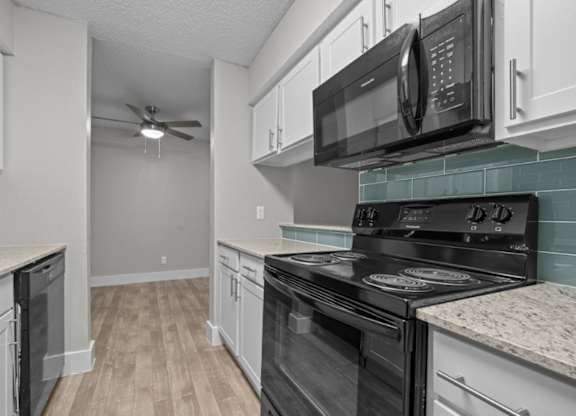 A kitchen with black appliances and white cabinets.