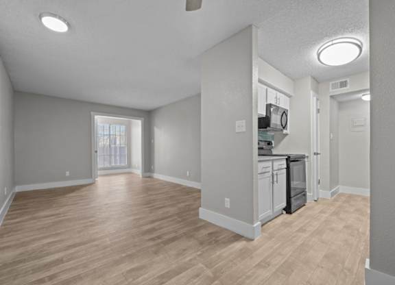 A spacious kitchen with wooden flooring and white walls.