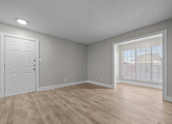 A room with a white door and a window with a view of a building outside.