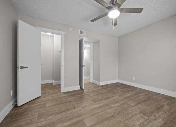 A room with a ceiling fan and wooden flooring.