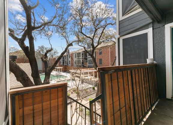 A view from a balcony looking out at a pool and houses.