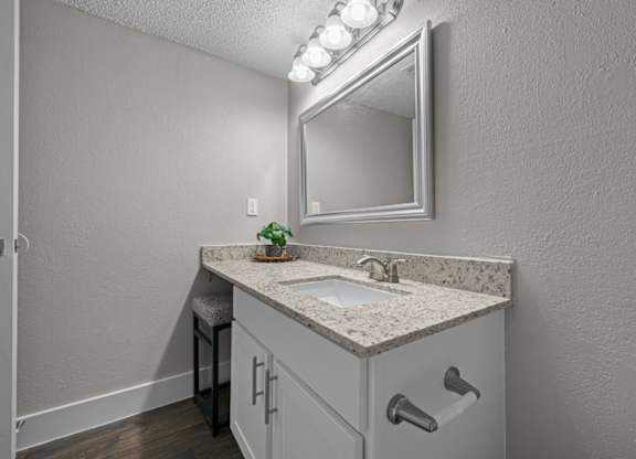 A bathroom with a sink, mirror, and lights.