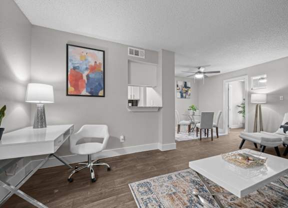 A living room with a white desk and white chairs.