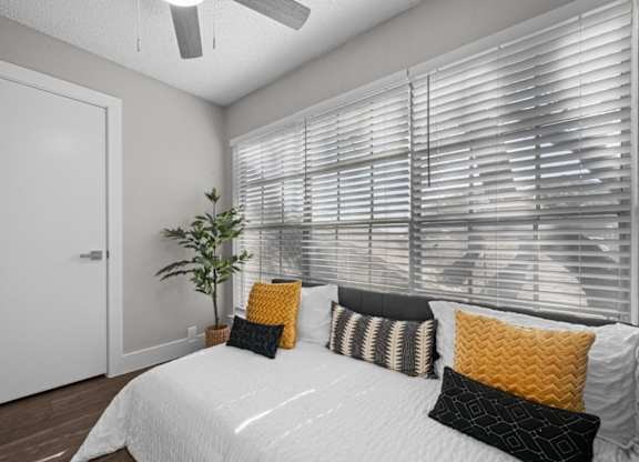 A bedroom with a bed, pillows, and a plant.