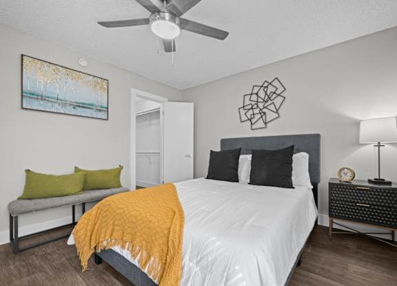 A bedroom with a bed, nightstand, and a painting on the wall.