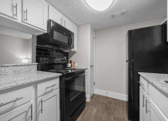 A kitchen with black appliances and white cabinets.