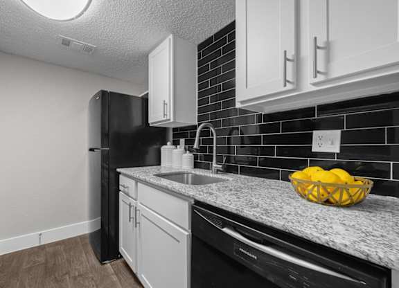 A kitchen with black appliances and white cabinets.