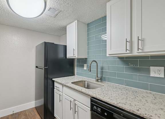 A kitchen with a black refrigerator and white cabinets.