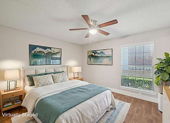 A bedroom with a bed, two lamps, a ceiling fan, and two pictures on the wall.