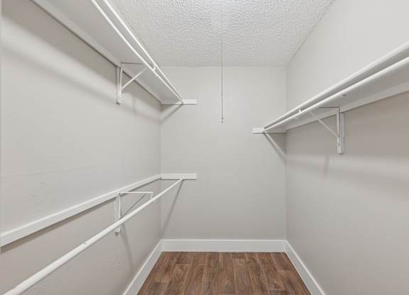 A white closet with shelves and a wooden floor.