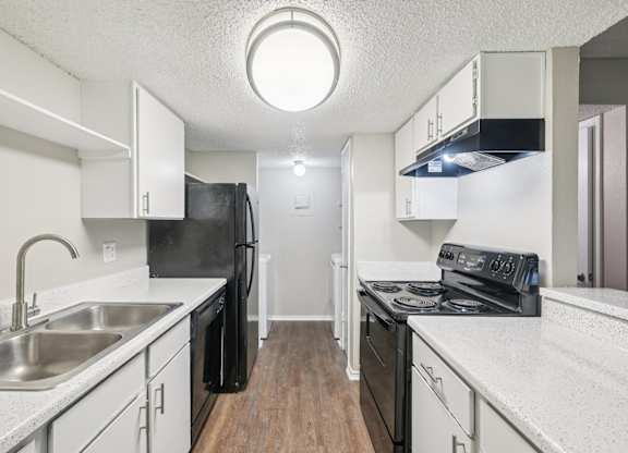 A kitchen with black appliances and white countertops.