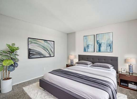 A bedroom with a large bed and two framed artworks on the wall.