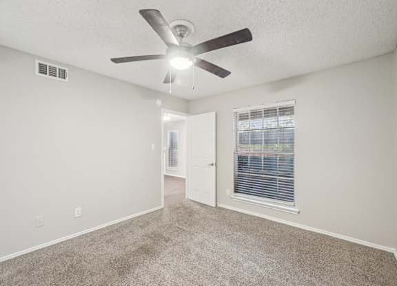 A room with a ceiling fan and carpeted floor.