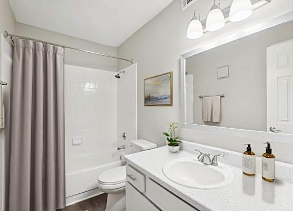 A bathroom with a white sink, toilet, and a grey shower curtain.