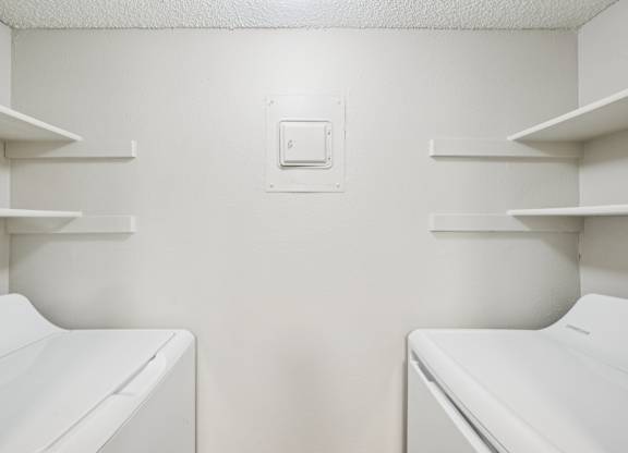Two white washing machines in a laundry room.