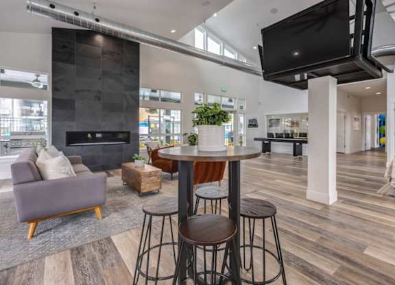 A modern living room with a grey couch, a wooden table, and a television mounted on the wall.