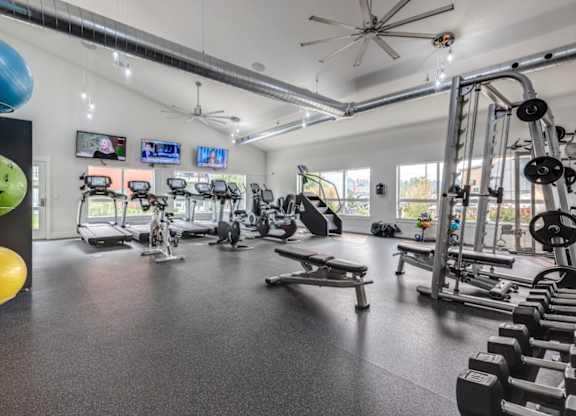 A gym with various exercise equipment and a fan.