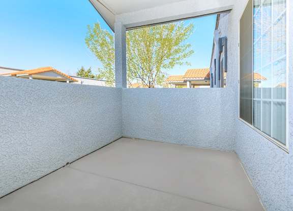 A balcony with a white wall and a grey floor.