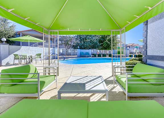 A pool area with green furniture and a green canopy.