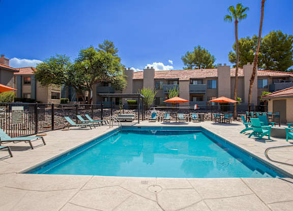 A swimming pool surrounded by lounge chairs and umbrellas.