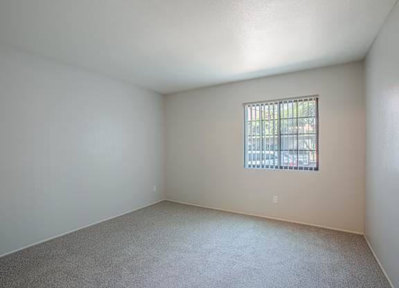 A room with a window and carpeted floor.