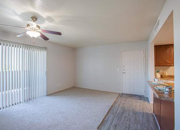A room with a ceiling fan and a window with blinds.