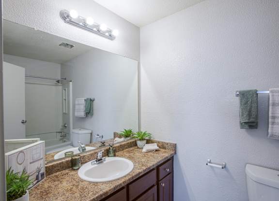 A bathroom with a sink, mirror, and towel rack.