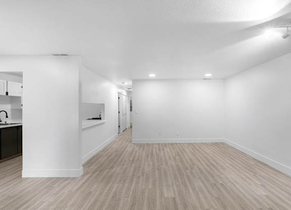 Spacious living room with wooden style flooring showing cutout feature looking into kitchen at The Rosewood Apartments in Vancouver, Washington.