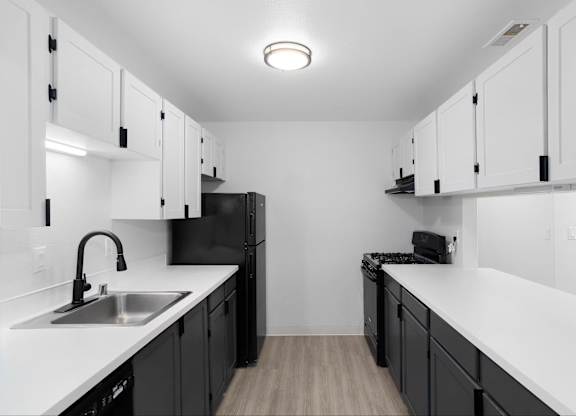 Modern kitchen with black cabinets and white countertops at The Rosewood Apartments in Vancouver, Washington.