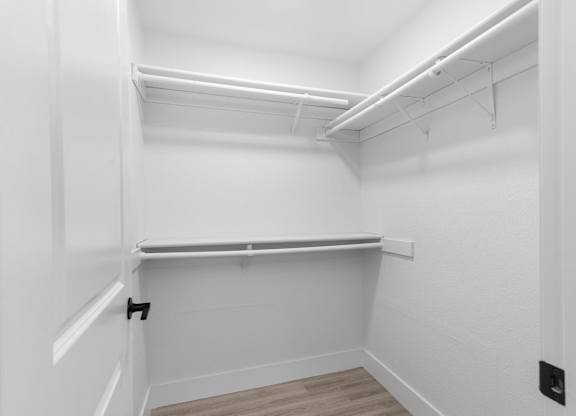 A white room with a shelf and a black electrical outlet.
