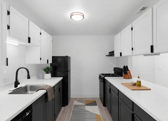 A kitchen with black cabinets and white countertops at The Rosewood Apartments in Vancouver, Washington.