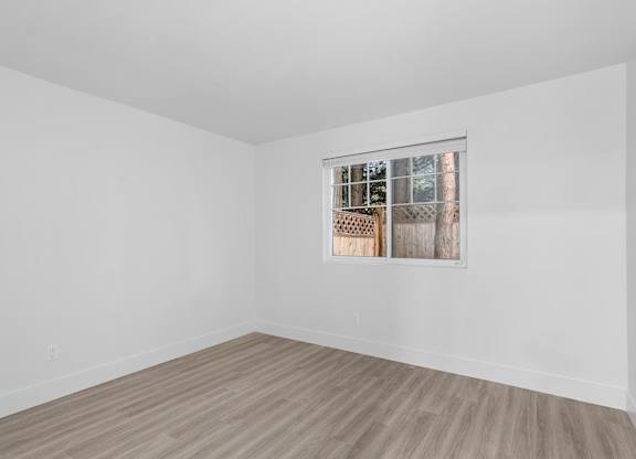 A room with a window and wooden flooring.