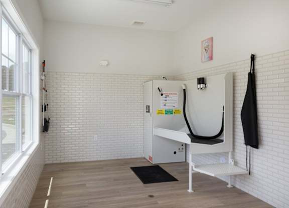 A white room with a hanger and ironing board.