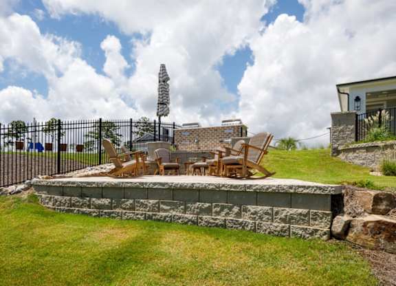 A patio with a table and chairs is surrounded by a stone wall.