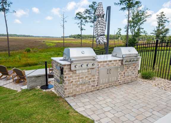 A brick outdoor kitchen with a grill and a table.