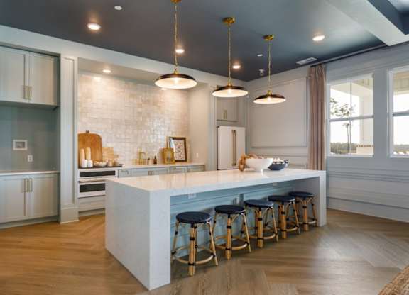 A kitchen with a white island and blue stools.
