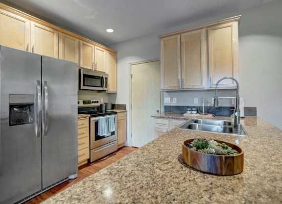 A kitchen with a granite counter top and stainless steel appliances.