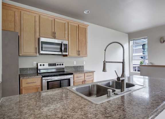 A kitchen with granite countertops and wooden cabinets.
