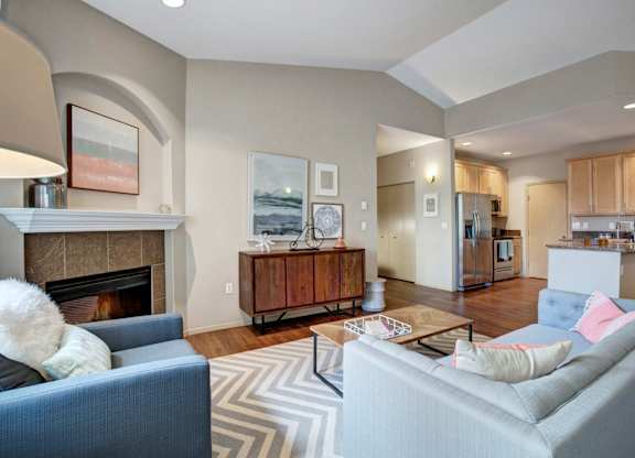 A living room with a grey couch and a fireplace.