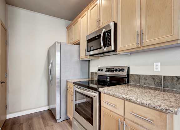 A kitchen with a refrigerator, oven, microwave, and stove.