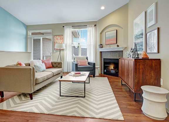 A living room with a fireplace and a striped rug.