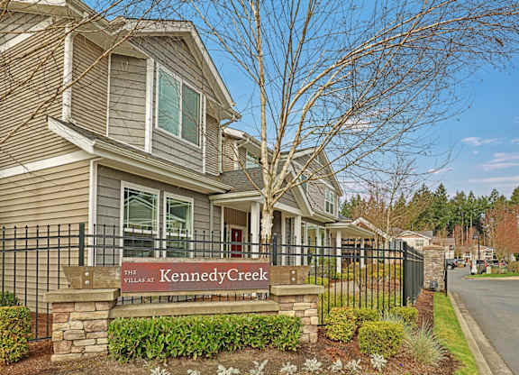 A house with a sign that says "The Kennedy Creek" in front of it.