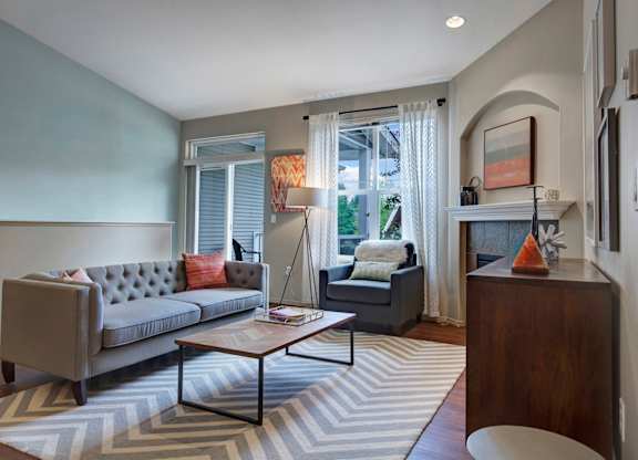 A grey couch with a red pillow sits in a living room.