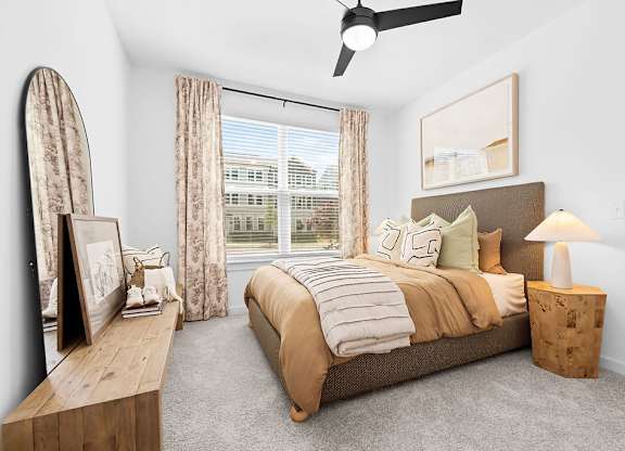 A bedroom with a large bed, a wooden bench, and a ceiling fan.
