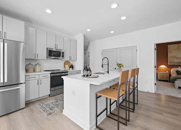 A modern kitchen with a white island and stainless steel appliances.